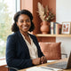 A professional portrait of a smiling woman in a bright, modern office space with warm-toned decor.